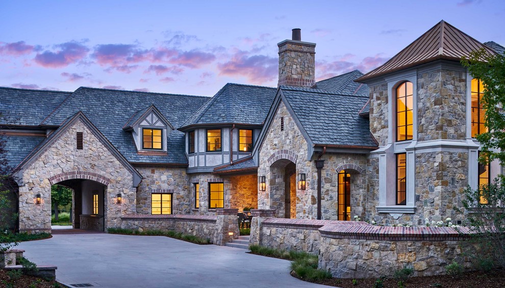 Photo of an expansive traditional three-storey house exterior in Denver with stone veneer.