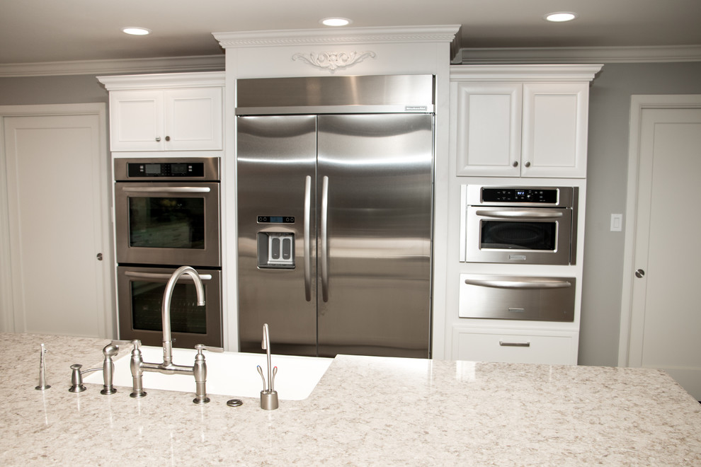 Huge transitional open concept kitchen photo with a farmhouse sink, recessed-panel cabinets, white cabinets, quartz countertops, beige backsplash, stone tile backsplash, stainless steel appliances and an island