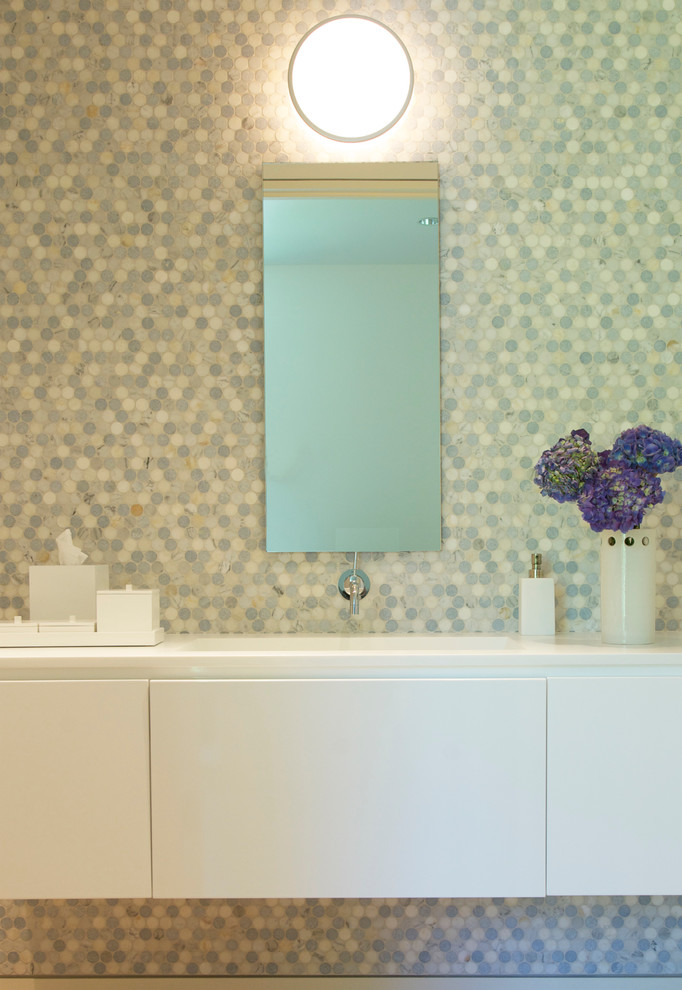 Small modern powder room in New York with flat-panel cabinets, white cabinets, an integrated sink and mosaic tile.