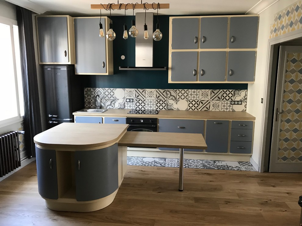 Photo of a mid-sized midcentury galley open plan kitchen in Angers with laminate benchtops, cement tiles and with island.