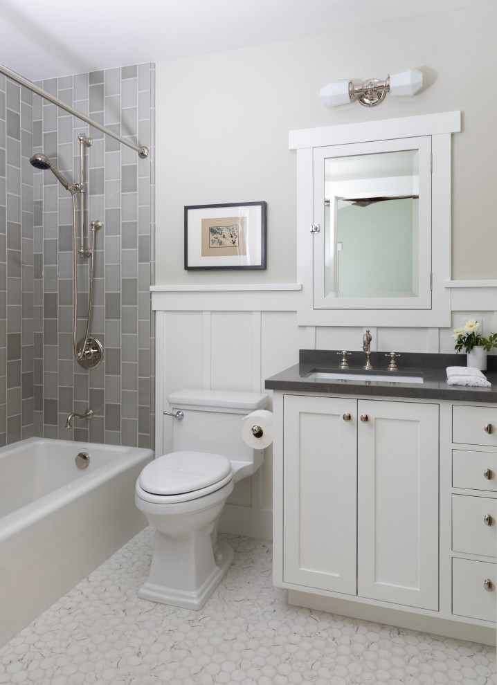 Bild på ett mellanstort amerikanskt grå grått en-suite badrum, med skåp i shakerstil, vita skåp, ett badkar i en alkov, en dusch/badkar-kombination, en toalettstol med hel cisternkåpa, grå kakel, keramikplattor, marmorgolv, ett undermonterad handfat, bänkskiva i kvarts och vitt golv