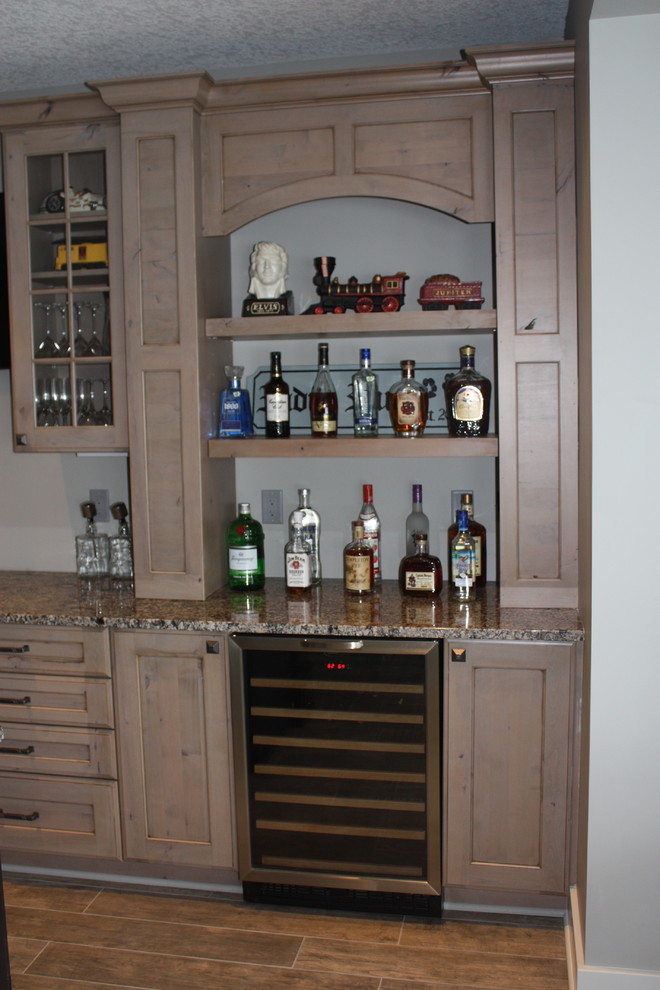 Photo of a transitional single-wall seated home bar in Other with an undermount sink, recessed-panel cabinets, grey cabinets, granite benchtops and porcelain floors.