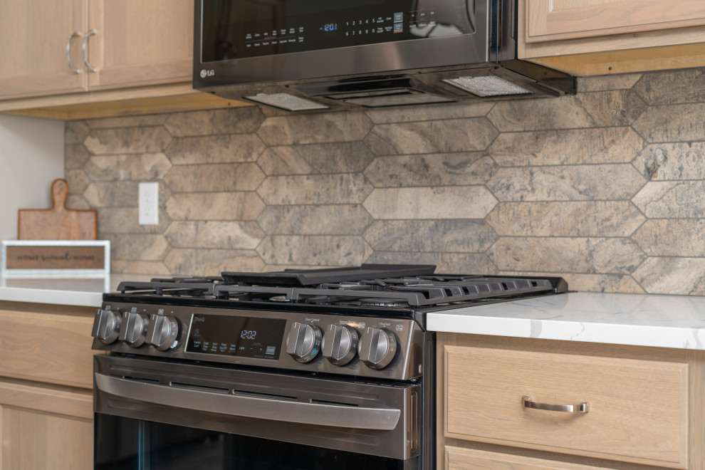 Kitchen - transitional kitchen idea with shaker cabinets, light wood cabinets, quartz countertops, beige backsplash, black appliances and white countertops