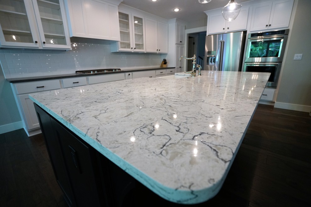 Eat-in kitchen - large transitional l-shaped dark wood floor and brown floor eat-in kitchen idea with a farmhouse sink, shaker cabinets, white cabinets, marble countertops, white backsplash, subway tile backsplash, stainless steel appliances and an island