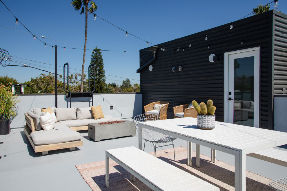 This is an example of a large modern patio in Los Angeles with an outdoor kitchen, decking and a roof extension.