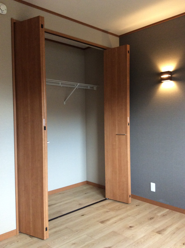 Foto di un armadio incassato unisex minimalista di medie dimensioni con ante lisce, ante in legno scuro, pavimento in legno verniciato, pavimento marrone e soffitto in carta da parati