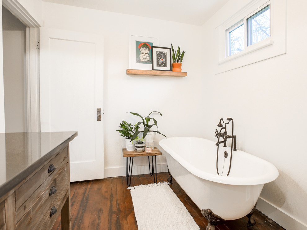 This is an example of a mid-sized country 3/4 bathroom in Portland with distressed cabinets, a claw-foot tub, white tile, white walls, medium hardwood floors, a drop-in sink, engineered quartz benchtops and brown floor.
