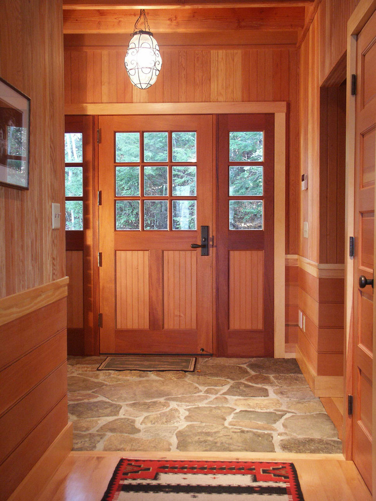 Modelo de puerta principal rural grande con puerta de madera en tonos medios, paredes marrones, suelo de piedra caliza, puerta simple y suelo gris