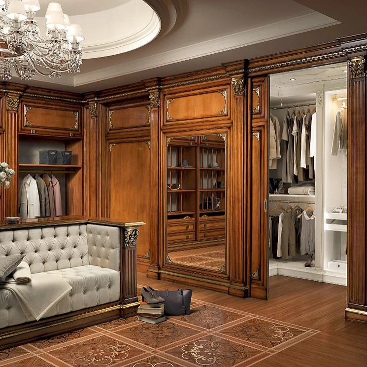 Photo of a mid-sized traditional gender-neutral storage and wardrobe in New York with louvered cabinets, dark wood cabinets, dark hardwood floors, brown floor and wood.