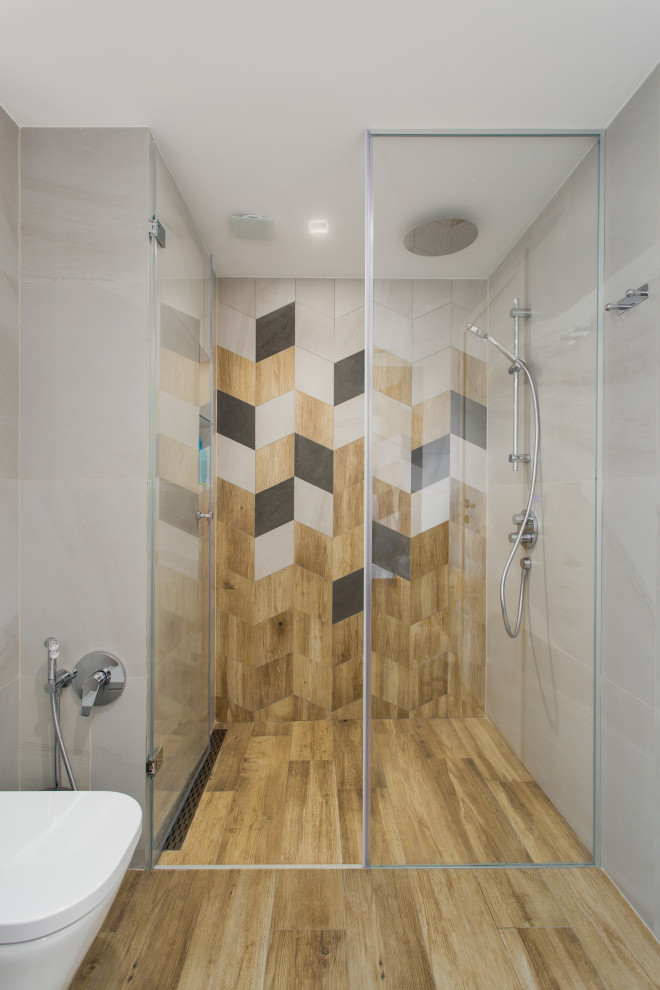 This is an example of a contemporary family bathroom in Other with flat-panel cabinets, medium wood cabinets, a built-in bath, a built-in shower, a wall mounted toilet, beige tiles, ceramic tiles, beige walls, wood-effect flooring, a wall-mounted sink, a hinged door, a single sink, a floating vanity unit and a drop ceiling.