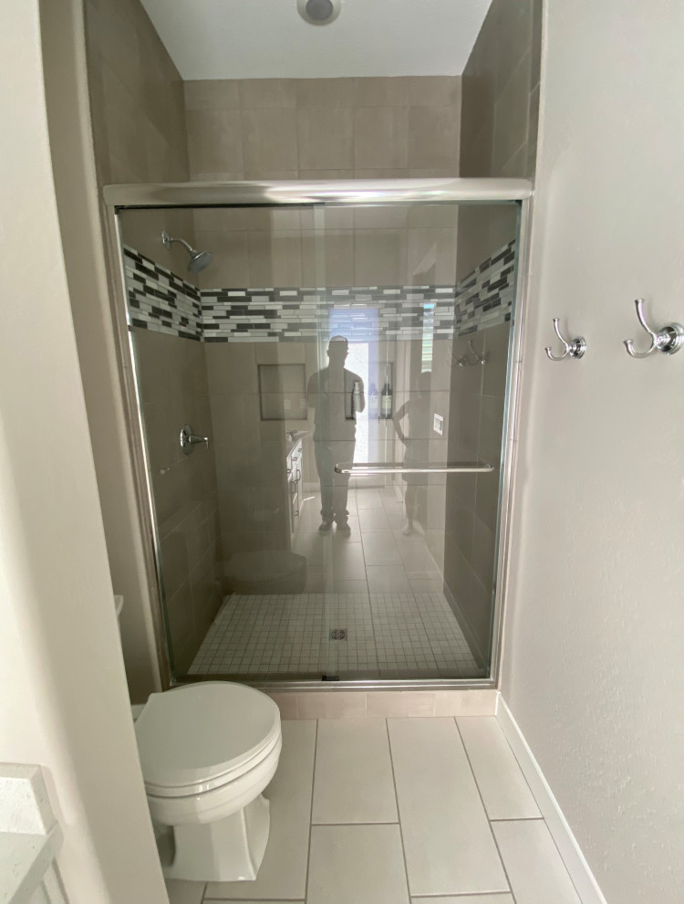 Idéer för ett mellanstort modernt badrum med dusch, med en dusch i en alkov, grå kakel, keramikplattor, klinkergolv i porslin, vitt golv, dusch med skjutdörr, en toalettstol med separat cisternkåpa och beige väggar