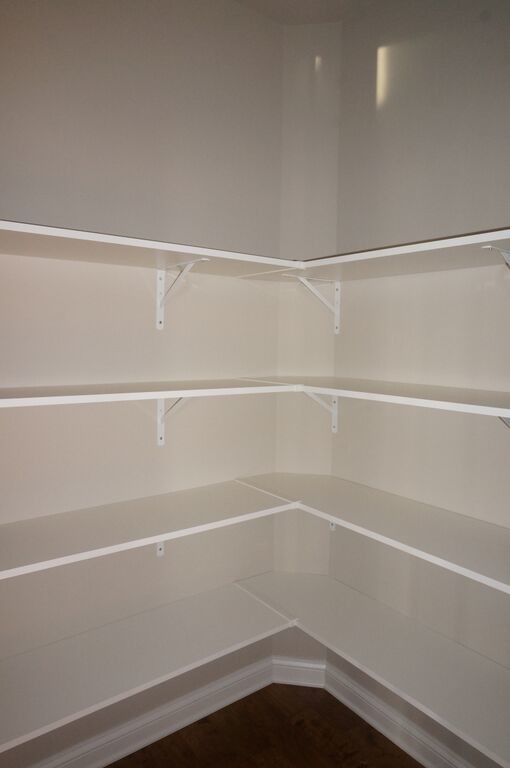 This is an example of a small traditional gender-neutral walk-in wardrobe in Other with open cabinets, white cabinets and dark hardwood floors.