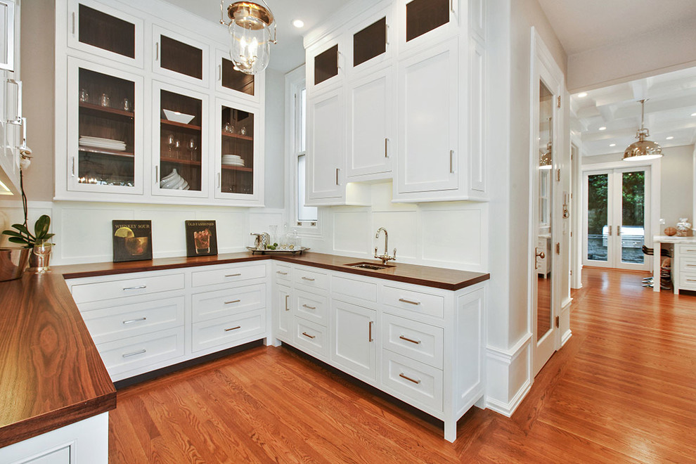 Photo of an expansive transitional u-shaped wet bar in San Francisco with an undermount sink, shaker cabinets, white cabinets, white splashback, medium hardwood floors, wood benchtops, timber splashback and brown floor.