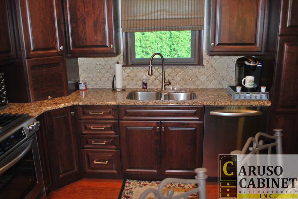 Small elegant l-shaped medium tone wood floor eat-in kitchen photo with a double-bowl sink, raised-panel cabinets, dark wood cabinets, quartzite countertops, beige backsplash, ceramic backsplash, stainless steel appliances and an island
