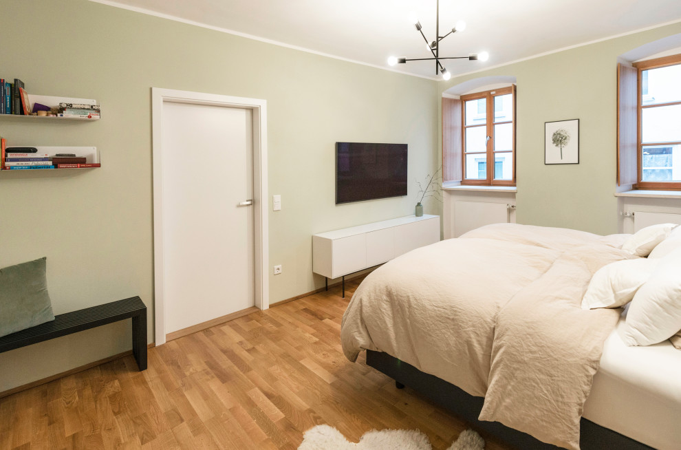 Mittelgroßes Modernes Schlafzimmer mit grüner Wandfarbe, braunem Holzboden und braunem Boden in Sonstige