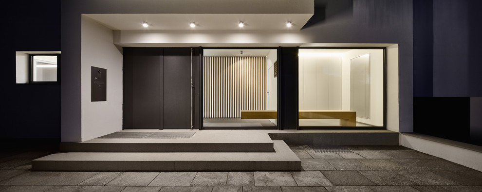 This is an example of a large contemporary foyer in Cologne with white walls, a single front door, a gray front door and concrete floors.