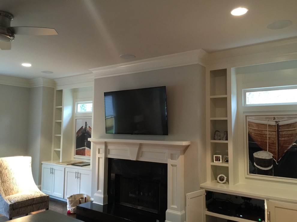 Photo of a large traditional enclosed family room in Atlanta with grey walls, a standard fireplace, a plaster fireplace surround and a wall-mounted tv.