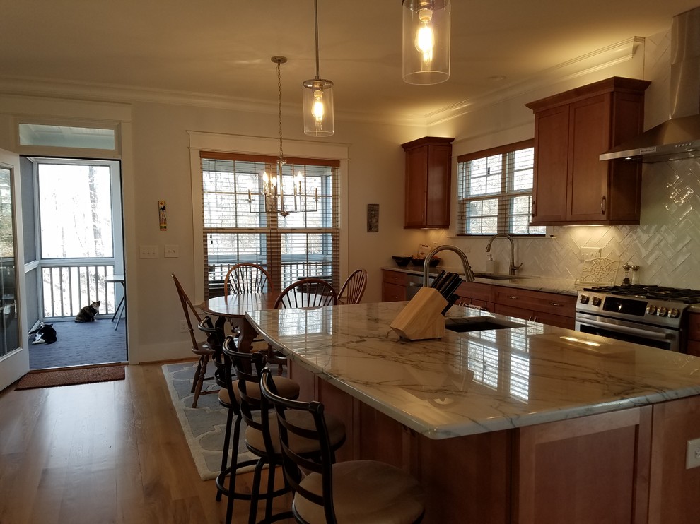 Mid-sized arts and crafts single-wall open plan kitchen in Raleigh with an undermount sink, shaker cabinets, light wood cabinets, quartzite benchtops, white splashback, ceramic splashback, stainless steel appliances, light hardwood floors, with island and orange floor.