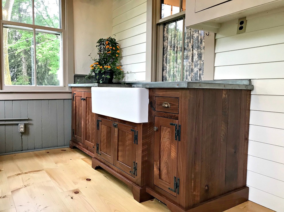 Design ideas for a mid-sized country utility room in Philadelphia with a farmhouse sink, shaker cabinets, dark wood cabinets, zinc benchtops, beige walls, light hardwood floors, brown floor and grey benchtop.