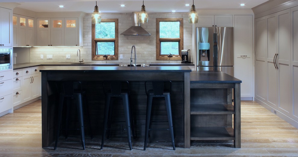 Large transitional u-shaped medium tone wood floor open concept kitchen photo in Calgary with an undermount sink, shaker cabinets, soapstone countertops, ceramic backsplash, stainless steel appliances and an island