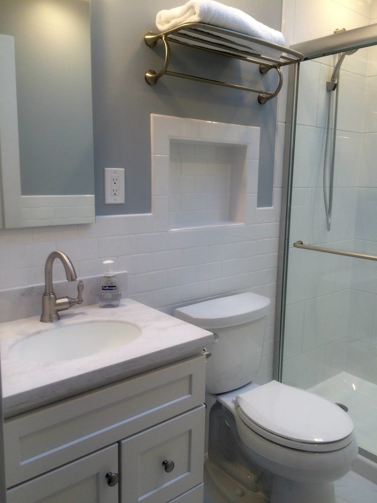 Inspiration for a small transitional master white tile and porcelain tile marble floor alcove shower remodel with recessed-panel cabinets, white cabinets, a two-piece toilet, blue walls, an undermount sink and solid surface countertops