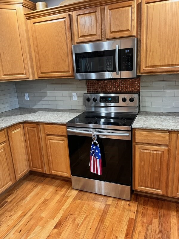 Kitchen - mid-sized transitional light wood floor kitchen idea with raised-panel cabinets, light wood cabinets, quartz countertops, beige backsplash, ceramic backsplash, stainless steel appliances and beige countertops