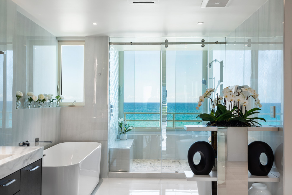 Mid-sized contemporary master wet room bathroom in Miami with dark wood cabinets, a freestanding tub, a bidet, white tile, stone slab, white walls, marble floors, an integrated sink, marble benchtops, white floor, a sliding shower screen, white benchtops, a shower seat, a double vanity and a floating vanity.
