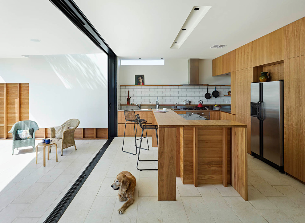 Photo of a modern l-shaped separate kitchen in Brisbane with flat-panel cabinets, medium wood cabinets, white splashback, subway tile splashback, stainless steel appliances, travertine floors and with island.