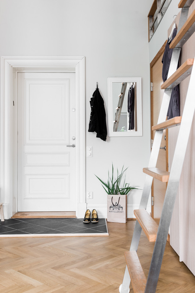 This is an example of a mid-sized transitional entry hall in Gothenburg with white walls, light hardwood floors, a single front door and a white front door.