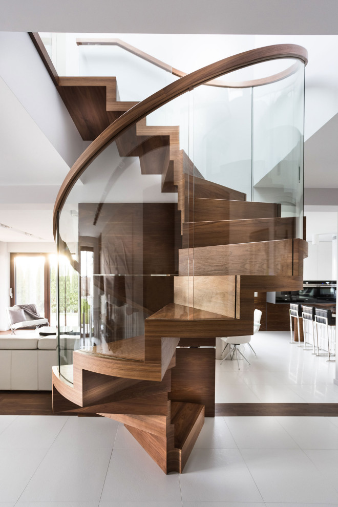 На фото: винтовая деревянная лестница в современном стиле с деревянными ступенями и стеклянными перилами с
