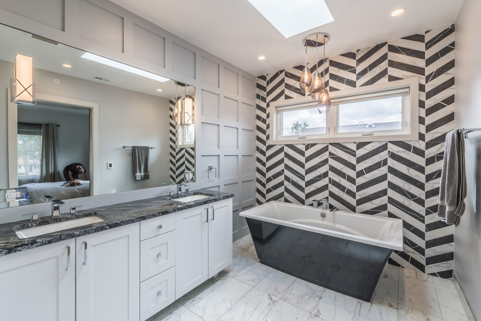 Mid-sized transitional master bathroom in Chicago with white cabinets, a freestanding tub, a one-piece toilet, black and white tile, grey walls, marble floors, a drop-in sink, white floor, a double vanity, a freestanding vanity and panelled walls.