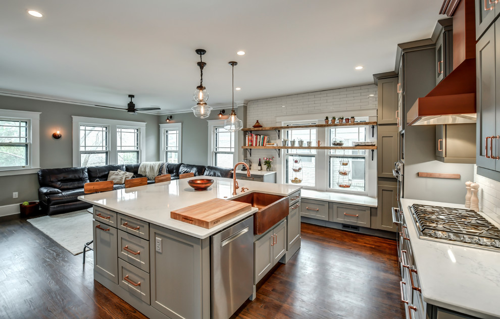 Inspiration for a transitional l-shaped kitchen in Atlanta with a farmhouse sink, shaker cabinets, grey cabinets, white splashback, subway tile splashback, medium hardwood floors, with island and brown floor.