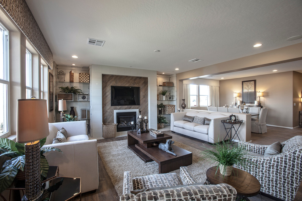 This is an example of a large traditional open concept living room in Las Vegas with beige walls, medium hardwood floors, a hanging fireplace, a tile fireplace surround and a wall-mounted tv.