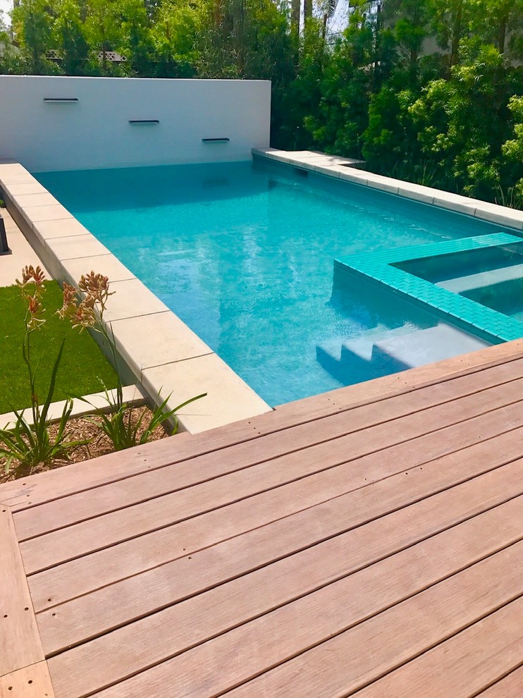 This is an example of a mid-sized modern backyard rectangular lap pool with decking.