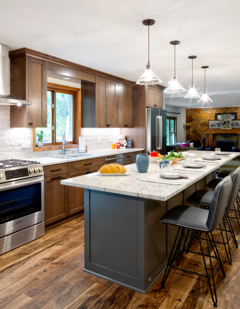 Mid-sized elegant galley vinyl floor eat-in kitchen photo in Minneapolis with a double-bowl sink, shaker cabinets, medium tone wood cabinets, granite countertops, white backsplash, ceramic backsplash, stainless steel appliances, an island and white countertops