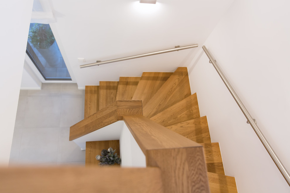 Gewendelte, Mittelgroße Moderne Holztreppe mit Holz-Setzstufen und Stahlgeländer in Sonstige