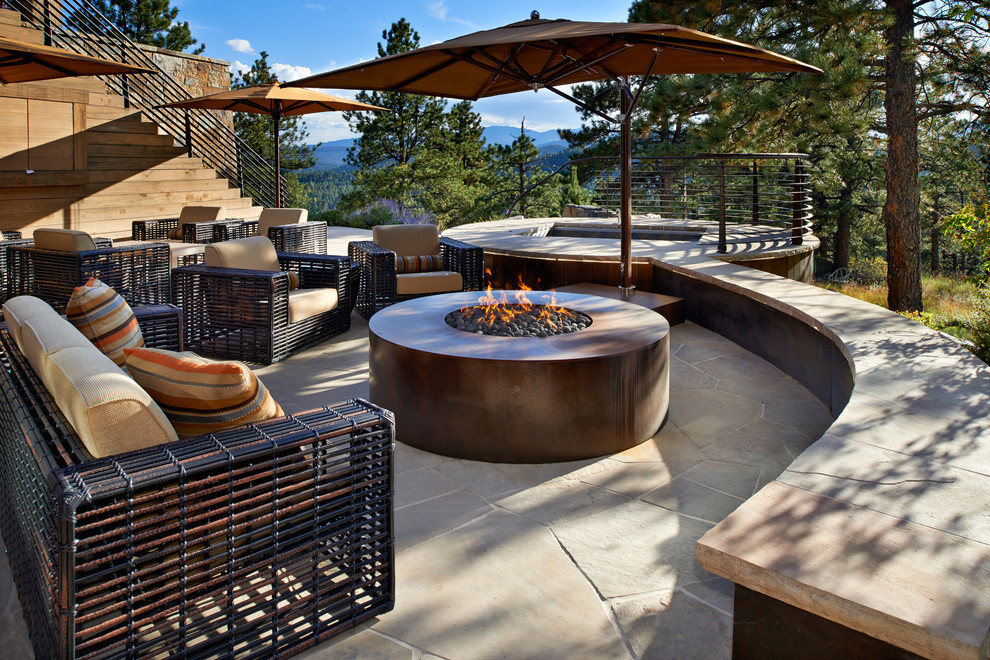 Photo of an expansive eclectic sloped xeriscape in Denver with a fire feature and natural stone pavers.