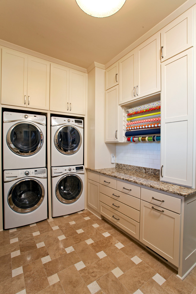 Design ideas for a large country u-shaped dedicated laundry room in Minneapolis with a farmhouse sink, shaker cabinets, white cabinets, granite benchtops, beige walls, ceramic floors and a stacked washer and dryer.