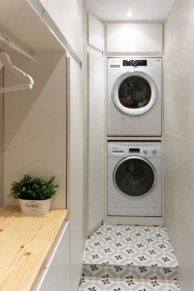 Small eclectic l-shaped utility room in Madrid with open cabinets, white cabinets, wood benchtops, white walls, ceramic floors, a stacked washer and dryer, grey floor and brown benchtop.