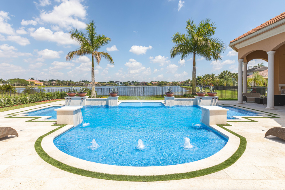 Design ideas for an expansive traditional backyard custom-shaped pool in Miami with a water feature and natural stone pavers.