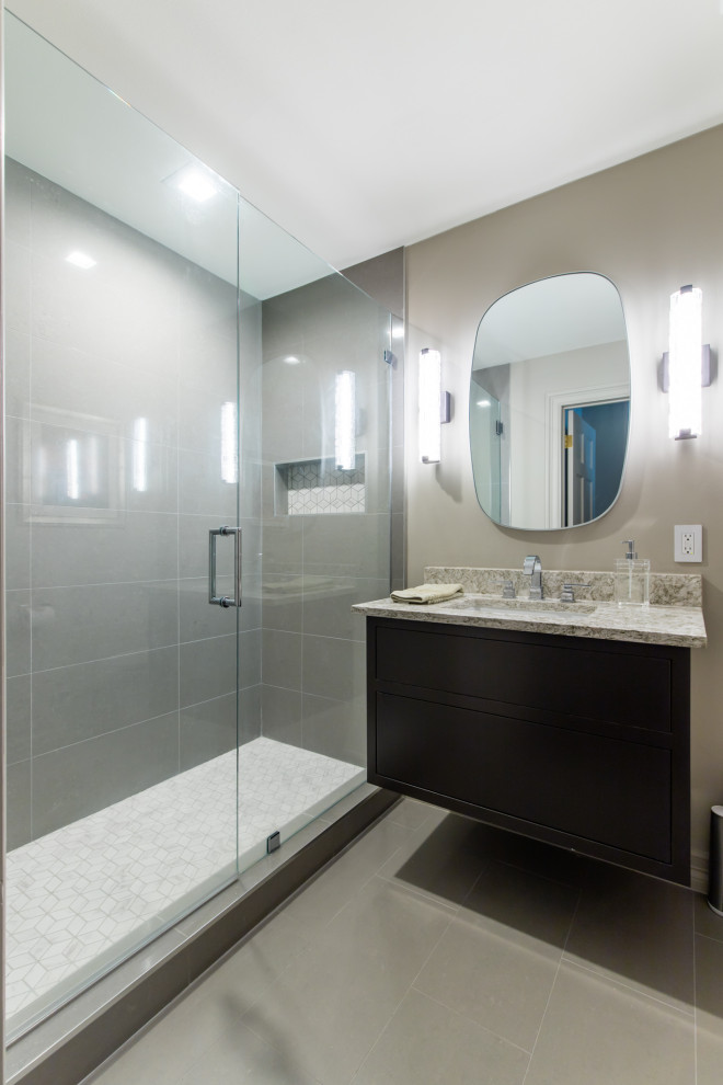 Design ideas for a mid-sized modern bathroom in Dallas with flat-panel cabinets, black cabinets, an alcove shower, gray tile, porcelain tile, beige walls, porcelain floors, an undermount sink, granite benchtops, grey floor, a hinged shower door and beige benchtops.