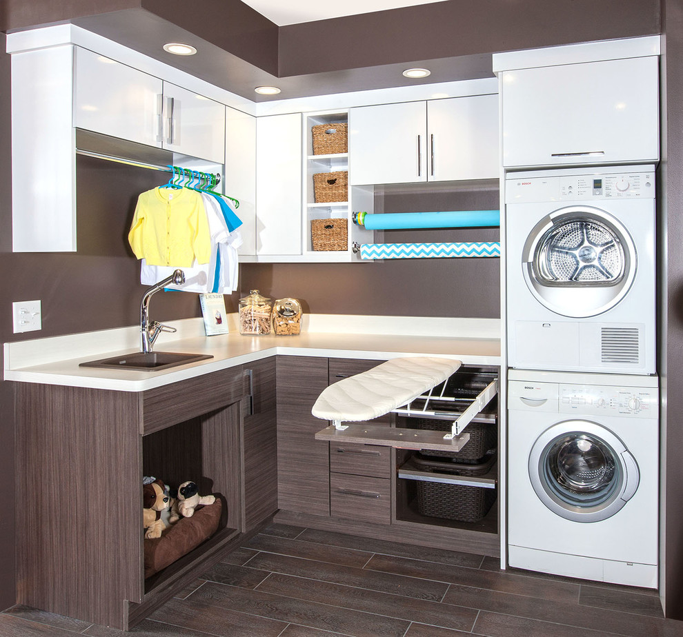 Mid-sized contemporary l-shaped utility room in Minneapolis with a drop-in sink, flat-panel cabinets, white cabinets, laminate benchtops, brown walls, porcelain floors and a stacked washer and dryer.