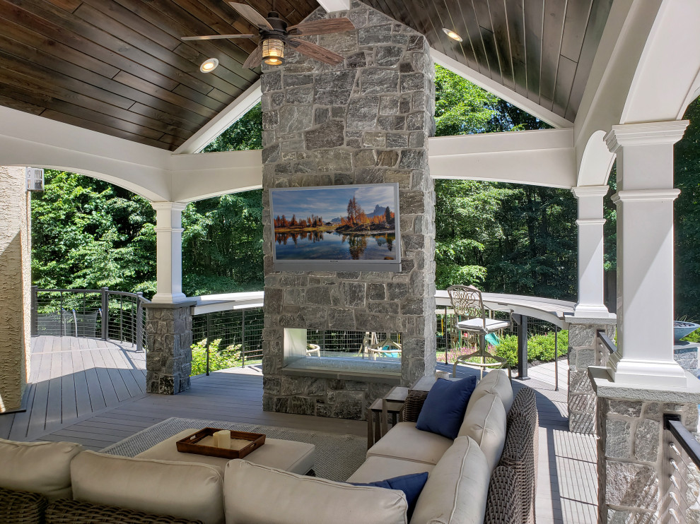This is an example of a mid-sized transitional metal railing back porch design with a fireplace.