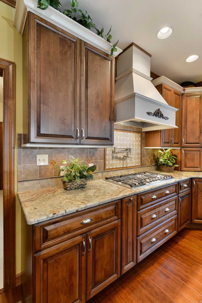 Example of a large transitional u-shaped medium tone wood floor eat-in kitchen design with beaded inset cabinets, medium tone wood cabinets, granite countertops, beige backsplash, mosaic tile backsplash, stainless steel appliances and an island