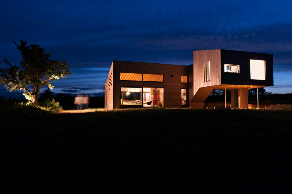 Large contemporary two-storey brown house exterior in Lyon with wood siding and a flat roof.