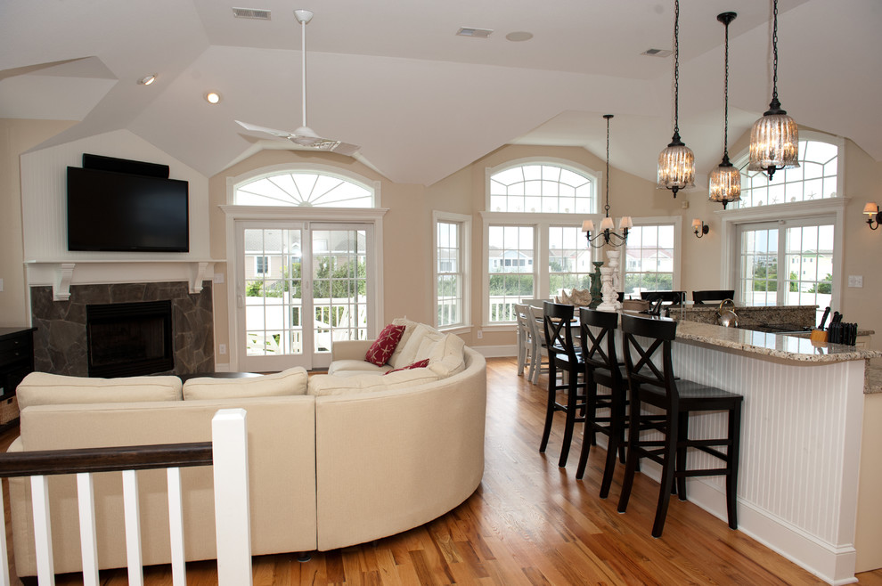 Photo of a large beach style open concept family room in Other with light hardwood floors, beige walls and a wall-mounted tv.