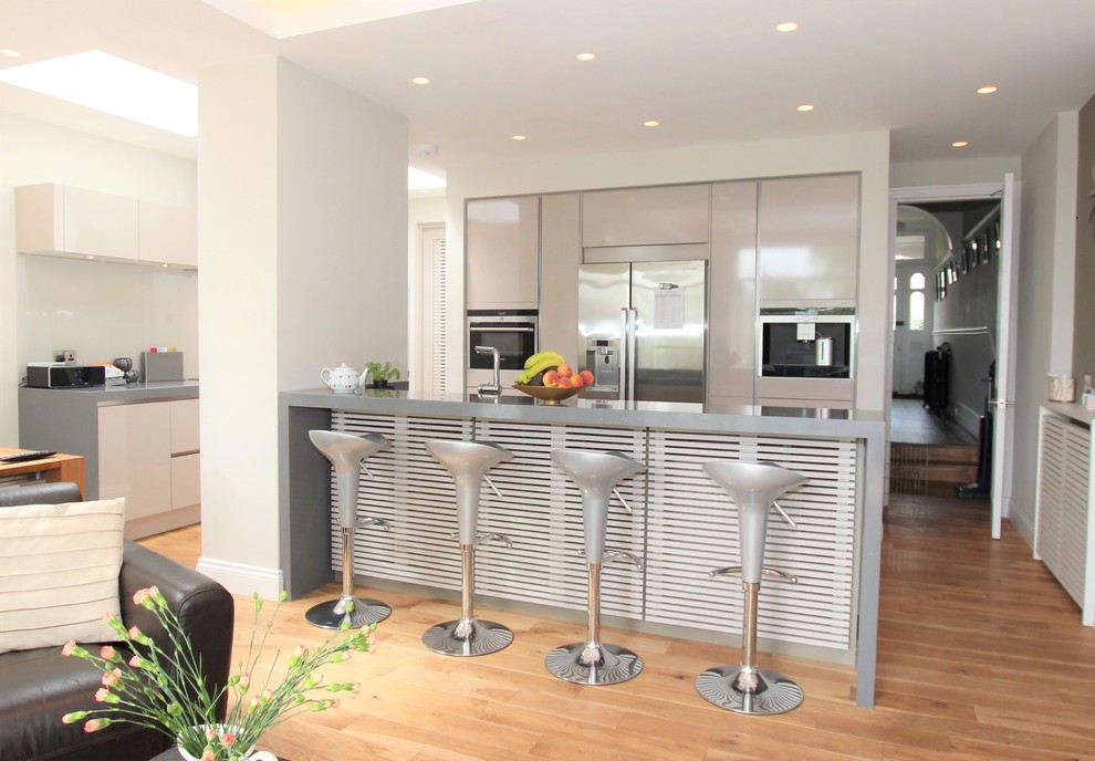 Modern kitchen in London with glass-front cabinets, quartzite benchtops and with island.