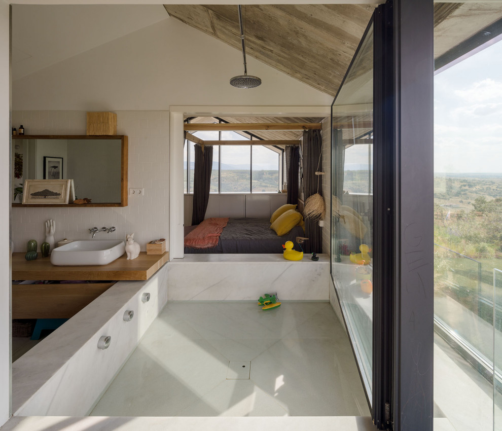 Imagen de cuarto de baño principal, doble y flotante de estilo de casa de campo grande con armarios tipo mueble, bañera empotrada, sanitario de pared, baldosas y/o azulejos blancos, baldosas y/o azulejos de cerámica, paredes blancas, suelo de madera en tonos medios, lavabo suspendido, encimera de madera, encimeras marrones y puertas de armario blancas
