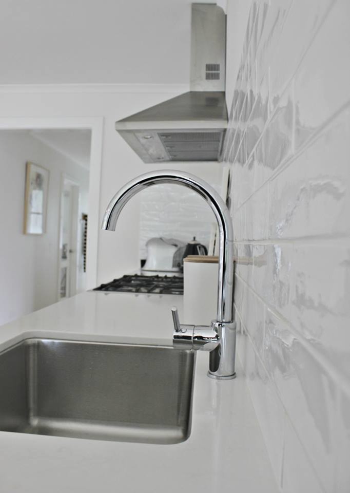 Inspiration for a transitional galley open plan kitchen in Hobart with an undermount sink, white cabinets, quartz benchtops, white splashback, ceramic splashback, stainless steel appliances, medium hardwood floors and with island.