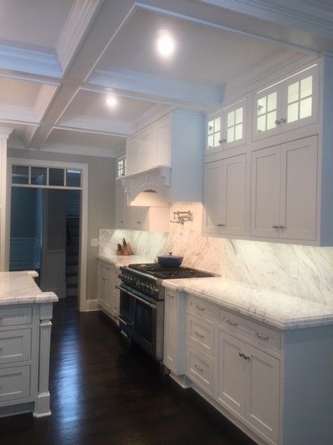 Open concept kitchen - large transitional l-shaped dark wood floor and brown floor open concept kitchen idea in Providence with a farmhouse sink, beaded inset cabinets, white cabinets, marble countertops, white backsplash, marble backsplash, paneled appliances and an island